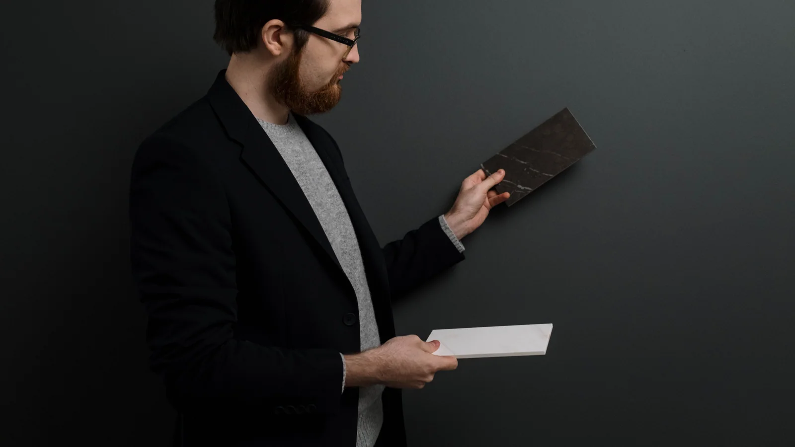Person comparing a dark tile sample with a light tile sample