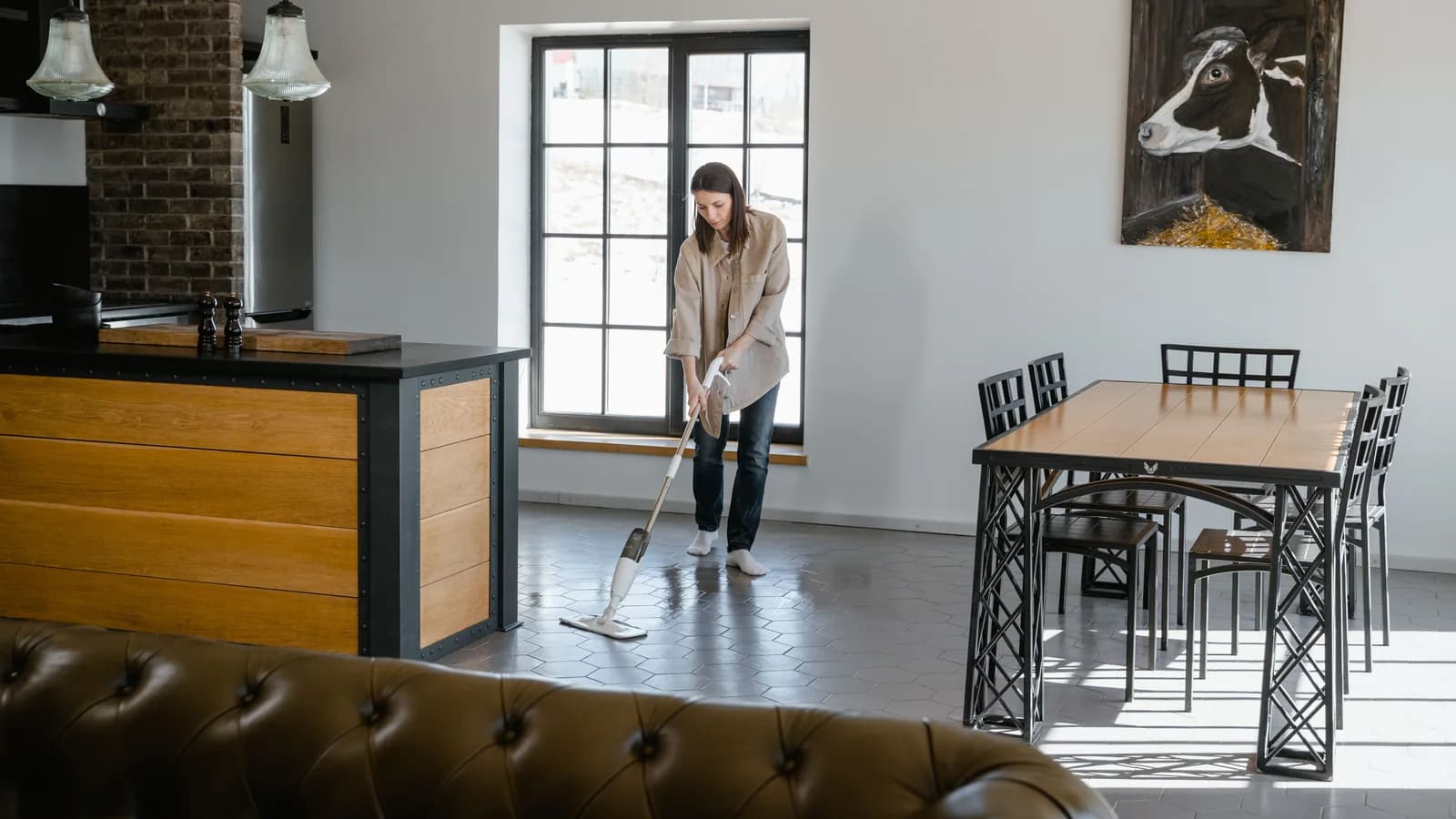Person cleaning a dark hexagonal tile floor with a floor mop