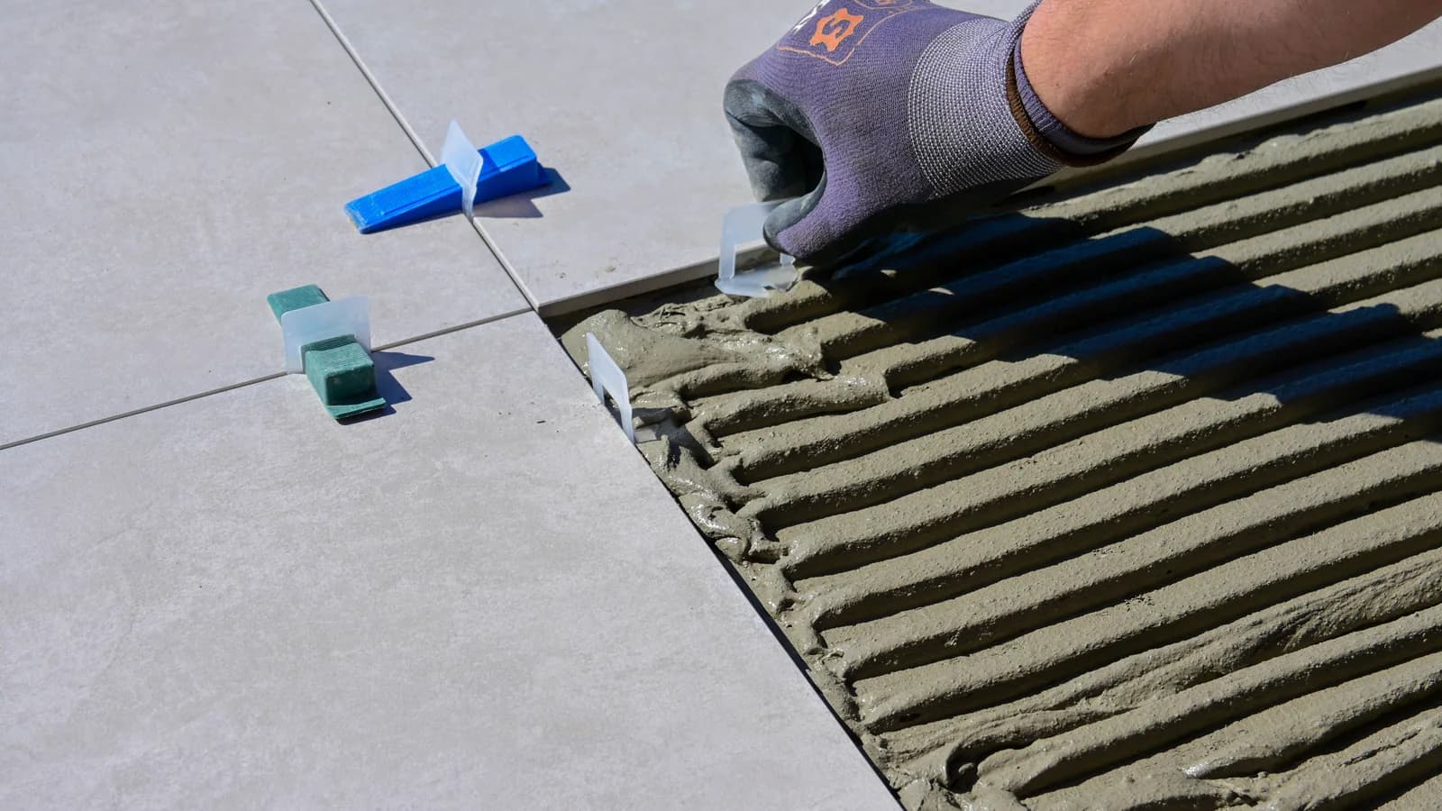 Gloved hand placing a tile levelling spacer during floor installation