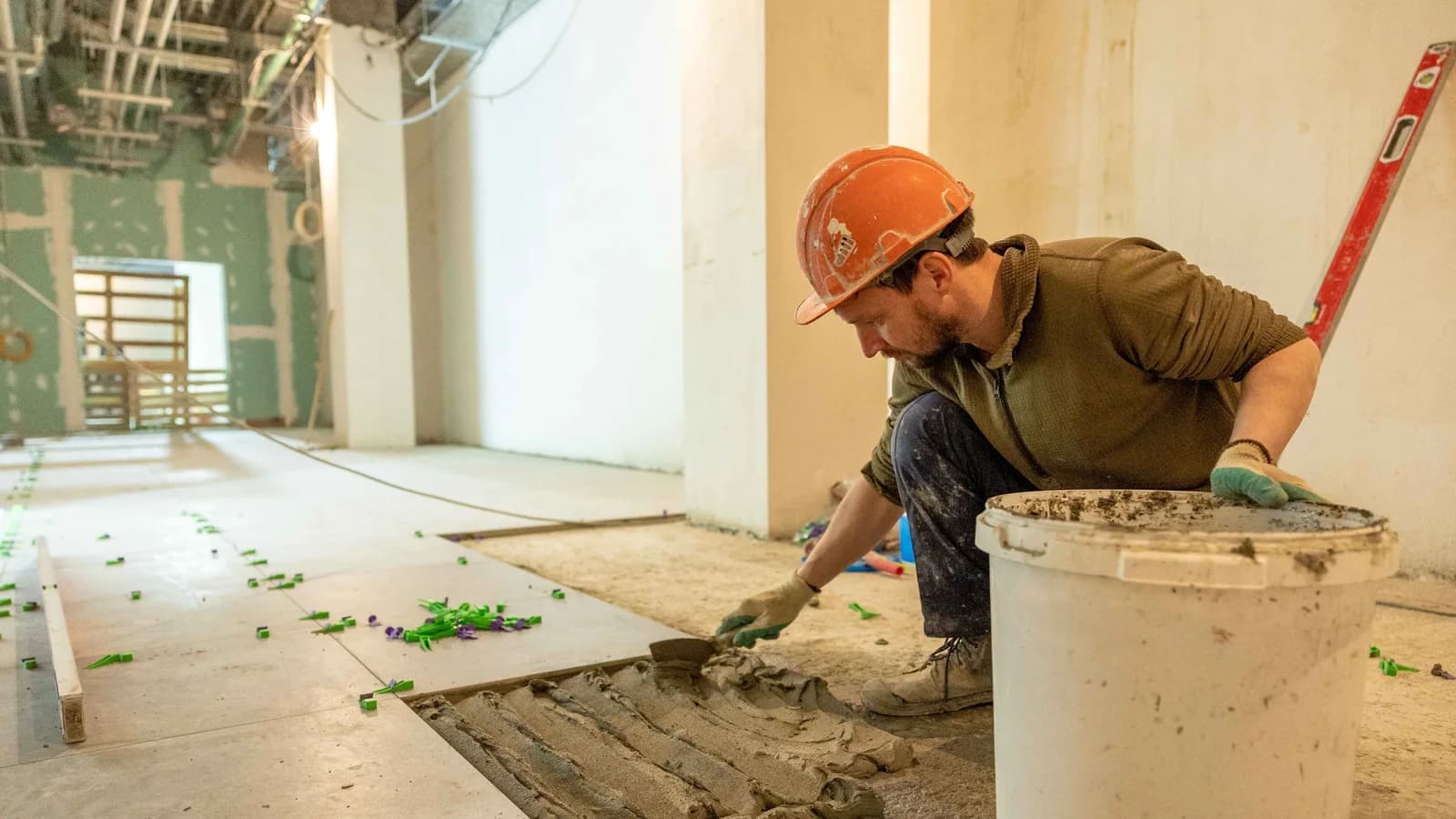 Tile installer spreading mortar while laying a large floor tile