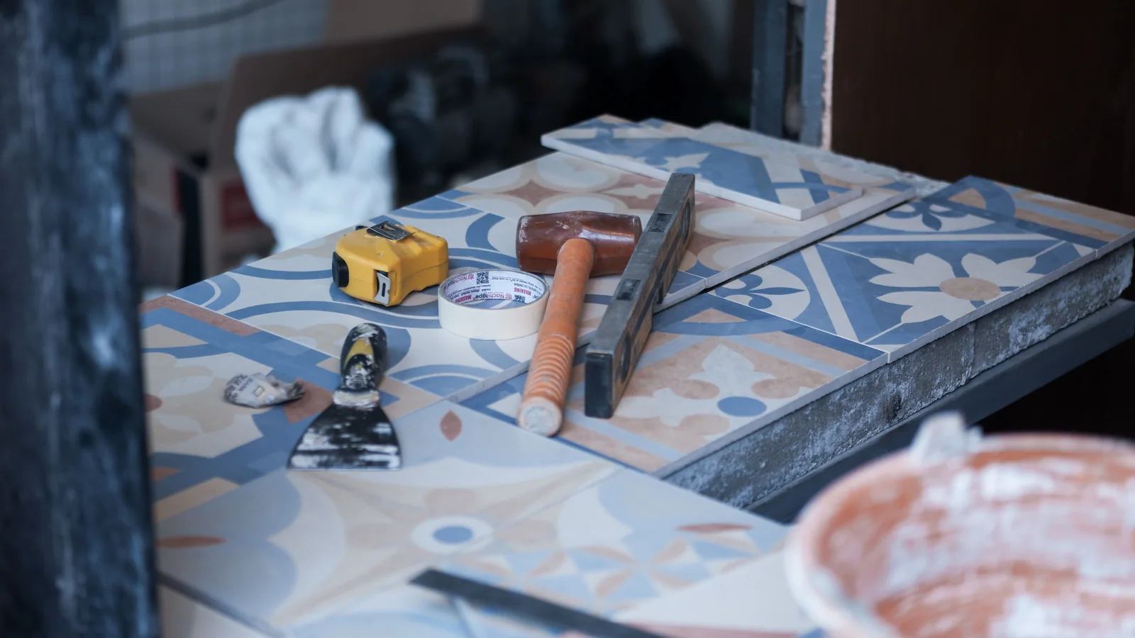 Tile samples with a tape measure, trowel, mallet, and level